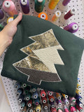 Folded dark green fabric with a tree-shaped patch on a light gray background