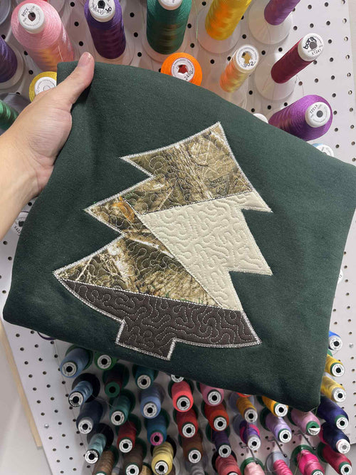 Folded dark green fabric with a tree-shaped patch on a light gray background