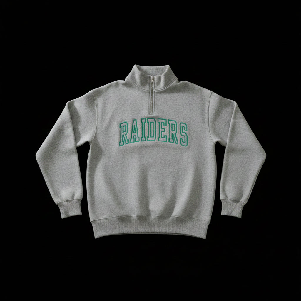 A light gray heathered quarter-zip sweatshirt with 'RAIDERS' printed in green arched block letters across the chest, displayed against a solid black background.