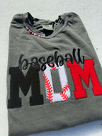 Folded gray t-shirt with 'Baseball Mom' text and baseball design on a light background