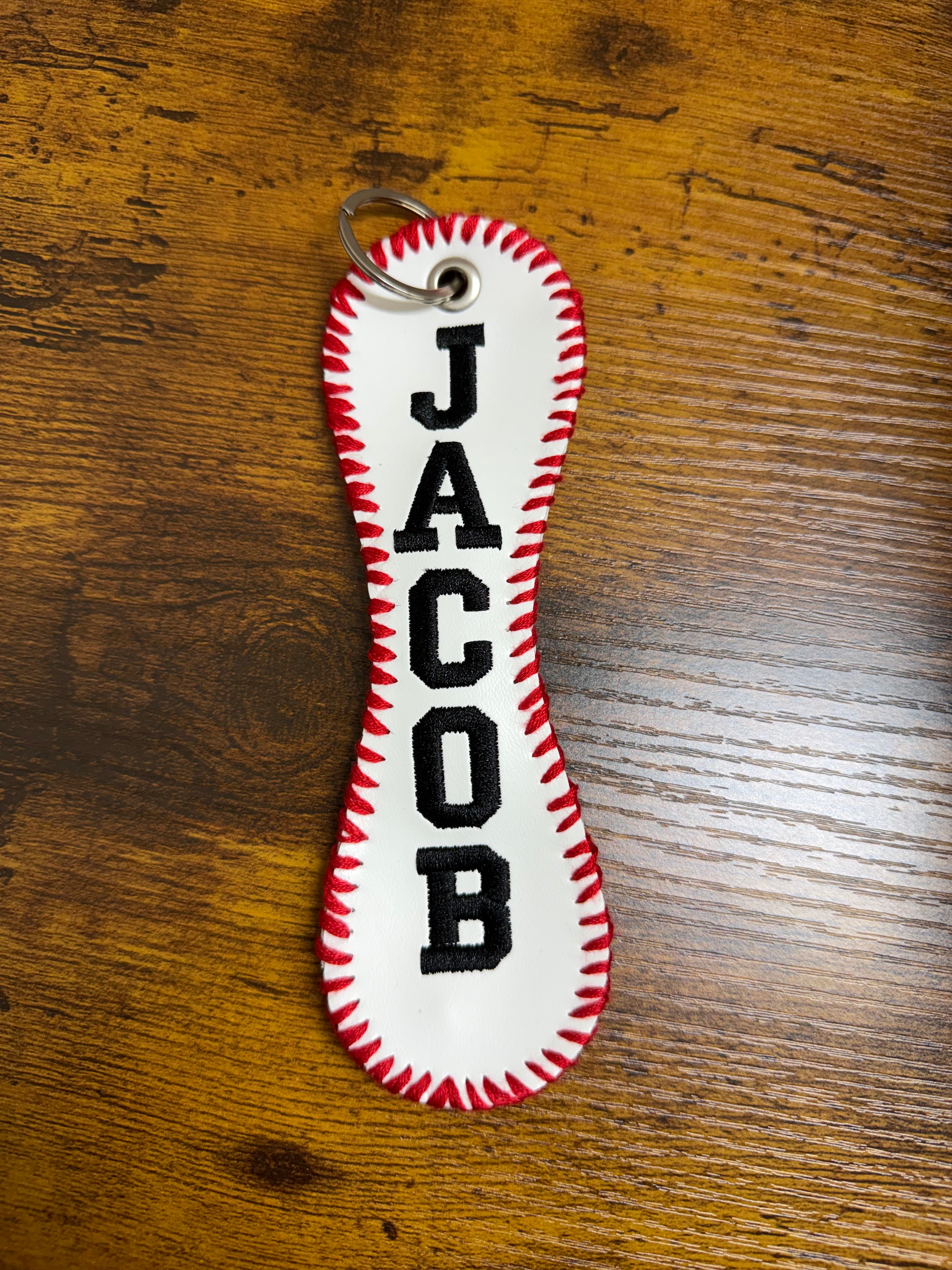 Keychain with 'JACOB' branding on a wooden surface