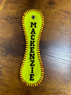 Yellow keychain with 'MACKENZIE' printed on it, placed on a wooden surface.