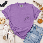 Purple t-shirt with ghost design, Converse shoes, and jeans on a wooden surface with Halloween decorations.