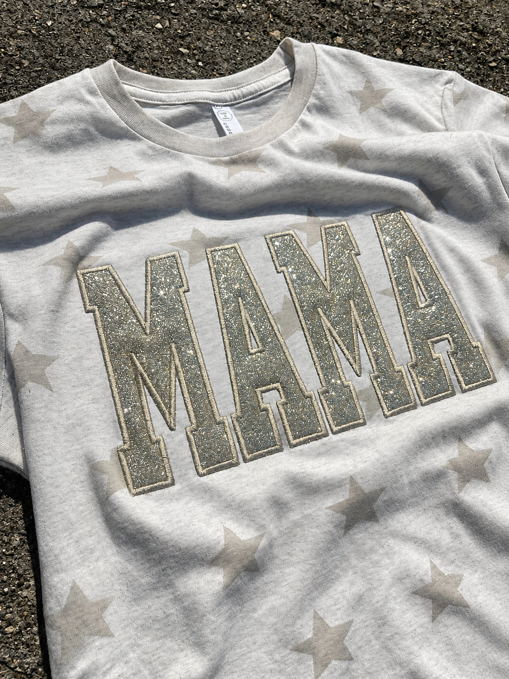 natural t-shirt with 'MAMA' in glittery letters on a star-patterned background