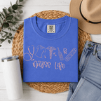 Blue t-shirt with 'Nurse Life' design on a woven mat with accessories.
