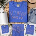 Blue t-shirt with 'Nurse Life' design on a woven mat with jeans and a hat.