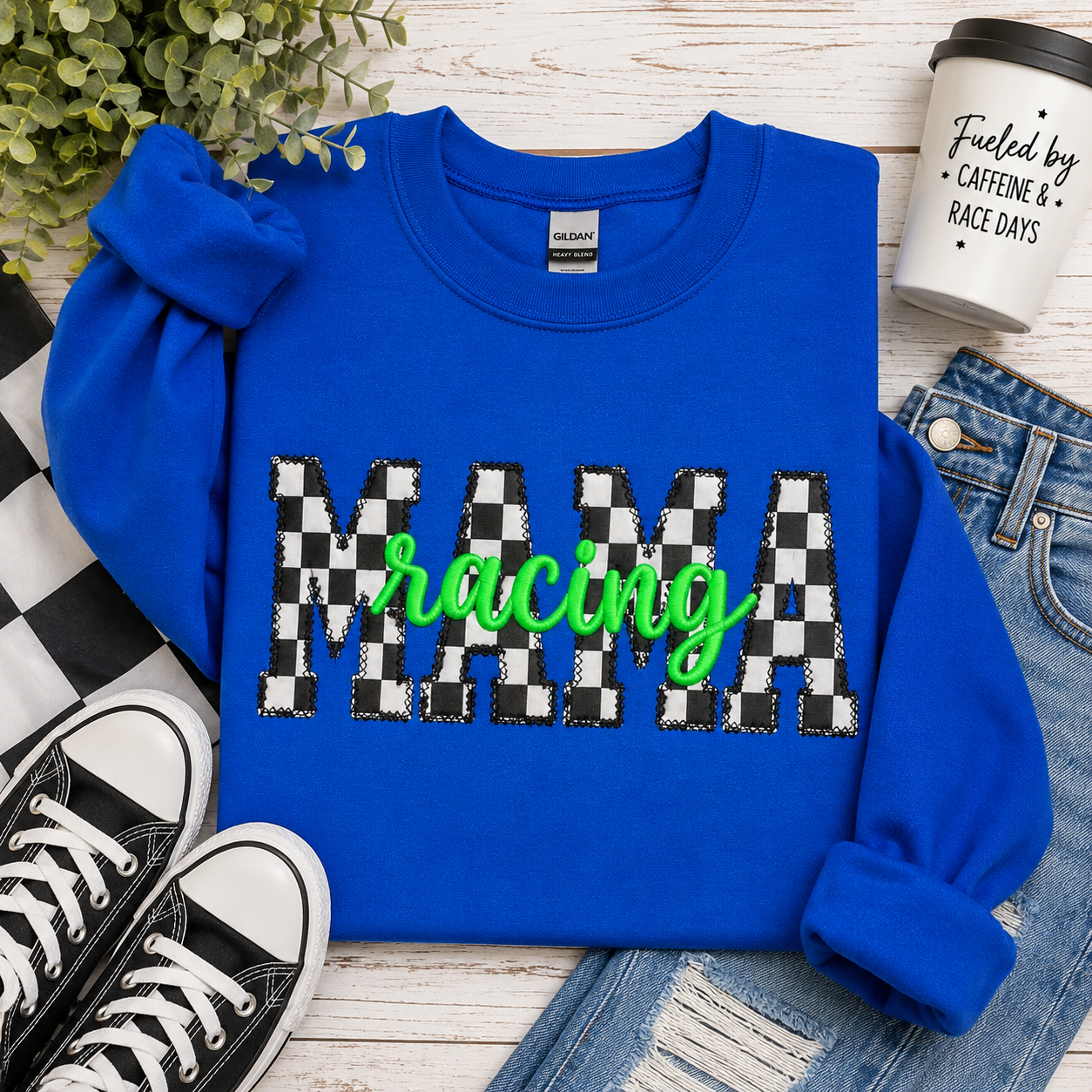 Blue sweatshirt with 'MAMA racing' text on a wooden surface with shoes and jeans.