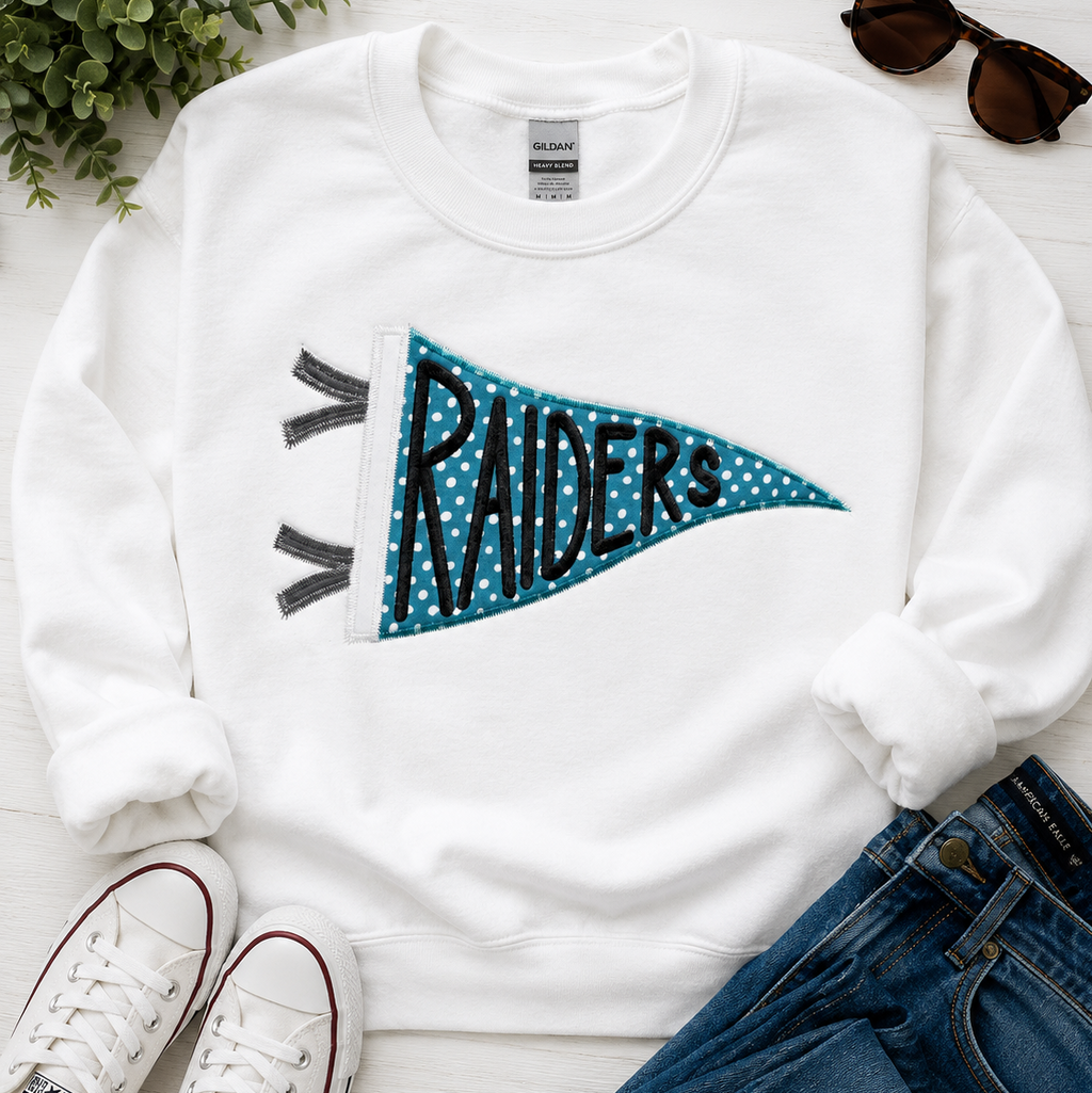 White sweatshirt with 'RAIDERS' design, paired with jeans and sneakers on a light wooden surface.